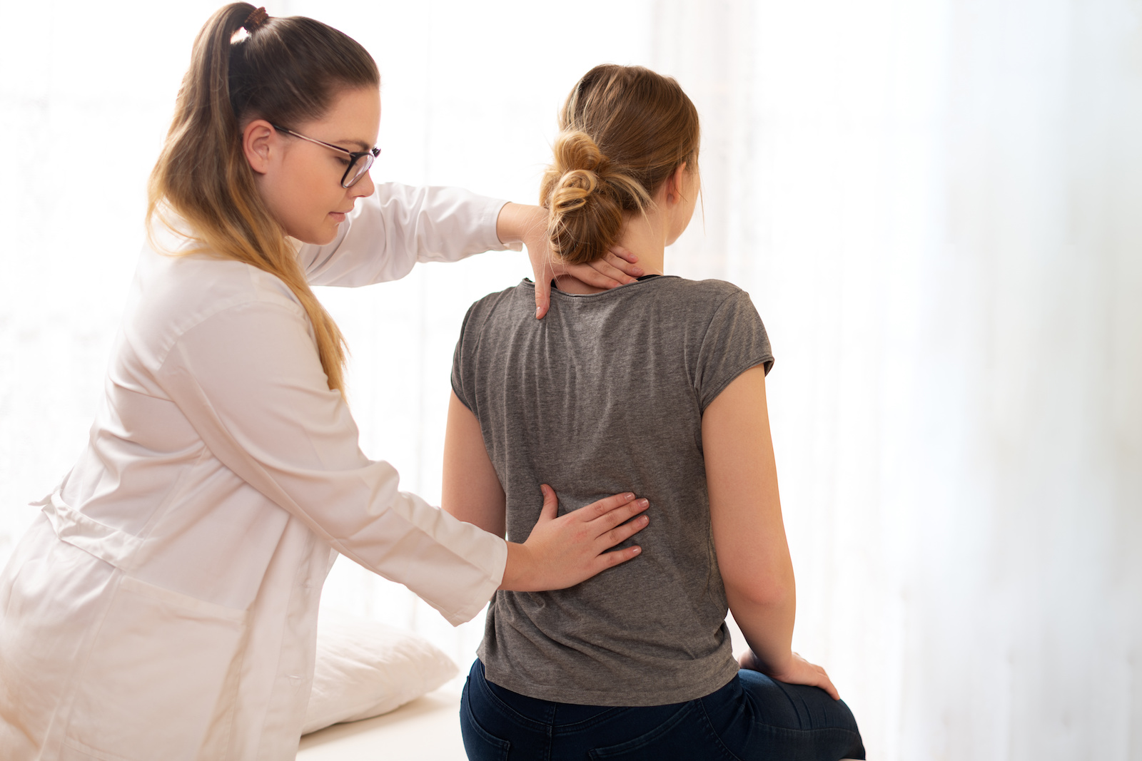Female physiotherapist or a chiropractor examining patients back. Physiotherapy, rehabilitation concept. chiropractic care benefits